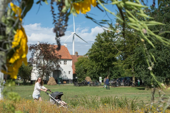Vrouw wandelt met buggy over het grasveld