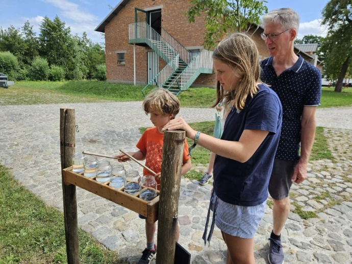 Kind maakt geluid met stokken en bokalen met verschillende inhoud water