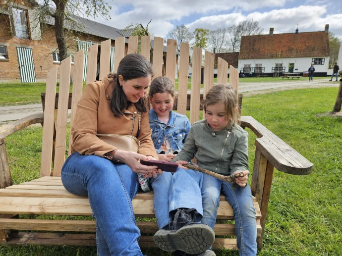 Mama met twee dochters zitten op een bank en kijken naar een gsm