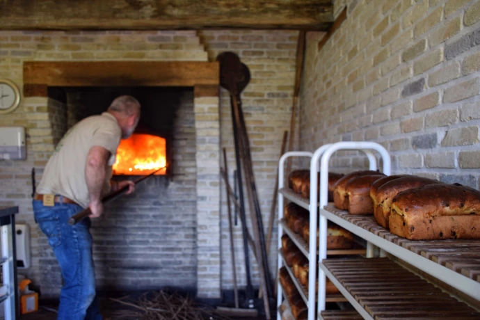 Huysbakker stopt brood in de houtgestookte oven