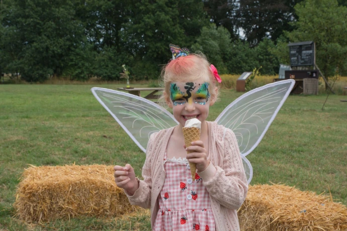 Kindje gesminkt met bloemenkapsel eet een ijsje
