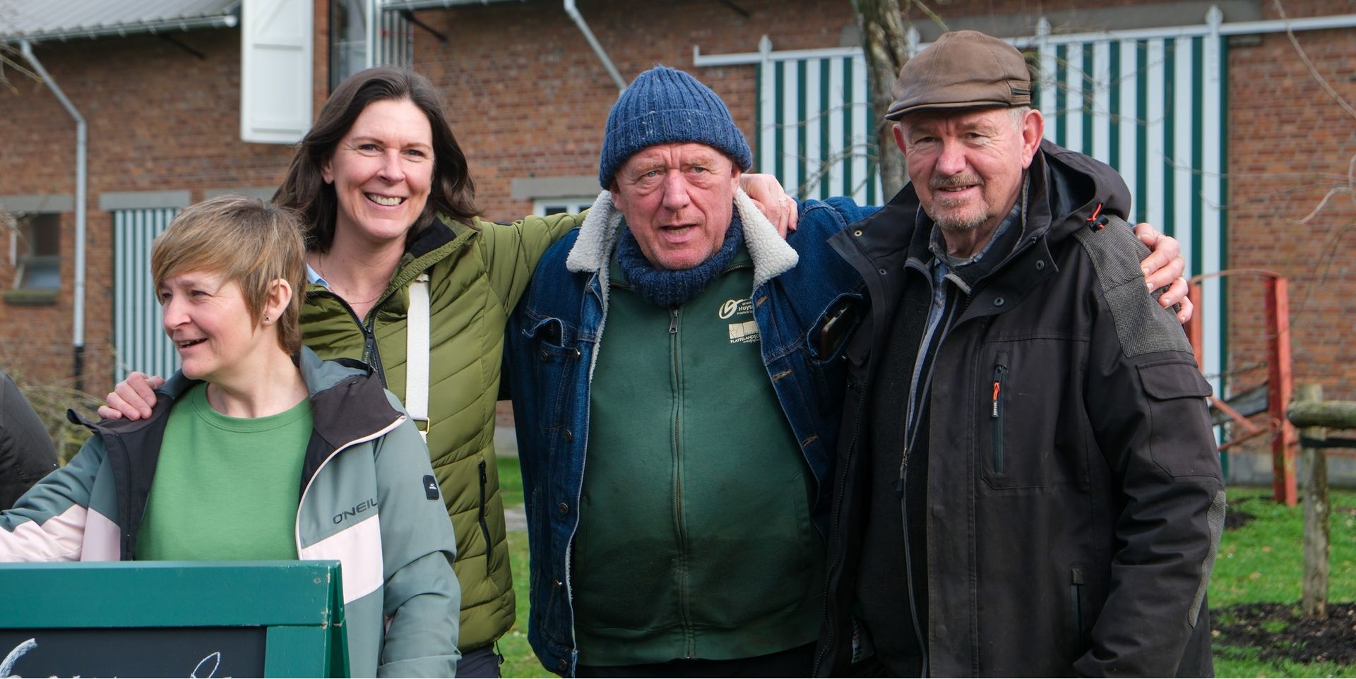 Vrijwilligers nemen elkaar vast voor de foto. Fotograaf: Monique Depestel